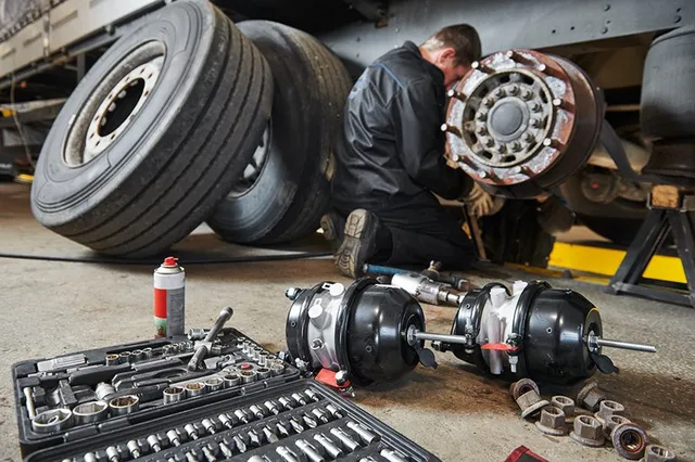 A man specializing in diesel mechanics is working on a tire in a garage.
