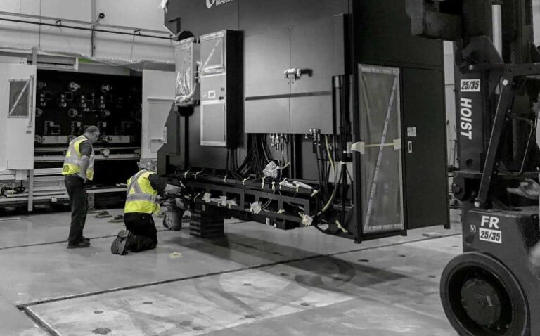 Two diesel mechanics operating a large machine in a warehouse.