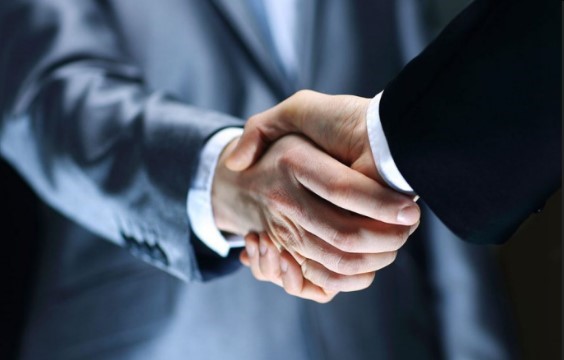 Two diesel mechanics shaking hands in front of a dark background.