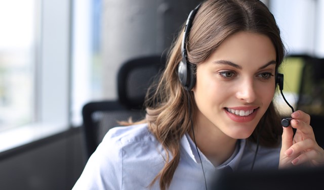 A woman wearing a headset while working at a computer and specializing in hiring diesel mechanics.
