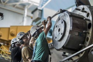 A group of diesel mechanics operating a machine in a factory.