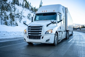 A white semi truck, driven by a diesel mechanic, maneuvering down a snowy road.