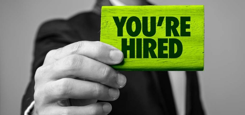 A diesel mechanic hiring manager holding up a sign that says you're hired.